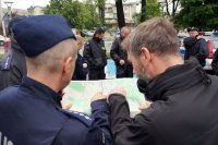 Dwóch policjantów przy mapie, jeden wskazuje obszar do przeszukania