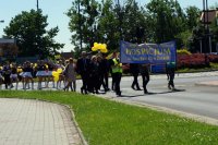 Uczestnicy marszu, niosą baner i przechodzą przez rondo