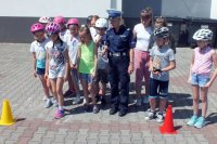 Policjantka pozuje z grupą uczniów w kaskach rowerowych