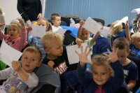 Dzieci pokazują zeszyty bezpiecznego przedszkolaka.