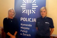 Po lewej Monika Grudziecka-Stefaniak, po prawej policjantka, w tle rollup z logo Policji