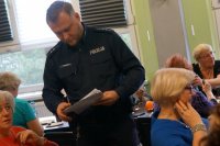 Policjant rozdaje ankiety seniorom