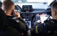 Policjant rozmawia przez telefon w radiowozie