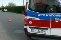 Policjant przy samochodzie sprawcy wypadku, na pierwszym planie karetka