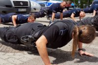 Policjantka wykonuje pompki, w tle inni policjanci