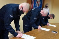 Policjanci składają podpisy na dokumencie ślubowania