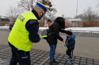Policjant wychyla się w stronę matki z dzieckiem