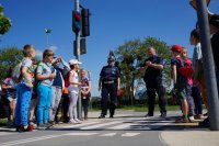 Policajnt stoi na przejściu dla pieszych, po obu stronach dzieci