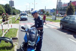 Policjant stoi przy motocyklu poszkodowanwego