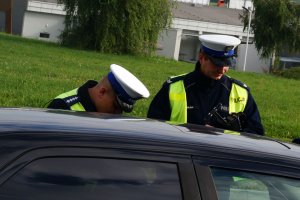 Policjanci stoją przy zatrzymanym samochodzie