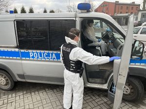 Policjanci ubrani w ubrania ochronne wsiadają do radiowozu