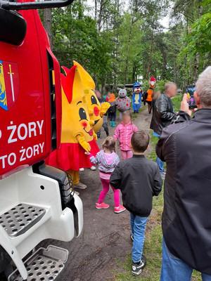 Na tle wozu strażackiego sznupek stoi z dziećmi