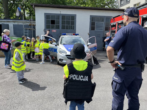 Policjant stoi z chłopcem ubranym w policyjną kamizelkę kuloodporną