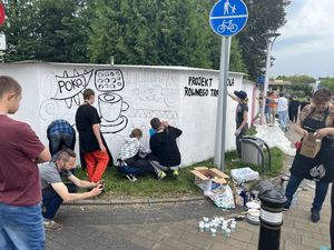 Młodzież maluje murale na ogrodzeniu