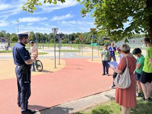 Policjant oraz uczestnicy egzaminu na kartę rowerową przed miasteczkiem ruchu drogowego