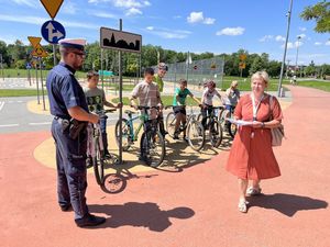 Policjant przy udziale dyrektor szkoły gratuluje zdanego egzaminu