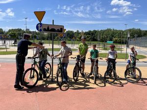 Policjant wręcza smycze i elementy odblaskowe dzieciom, które zdały egzamin na kartę rowerową