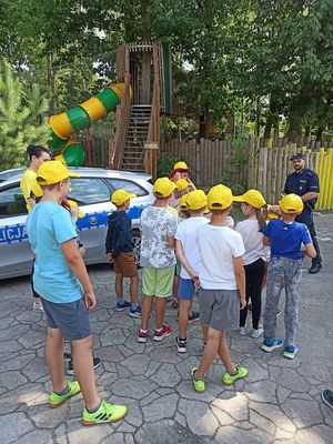 Policjant i dzieci podczas profilaktycznych zajęć w plenerze