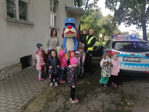 Policjant i Sznupek stoją wraz z dziećmi przy radiowozie