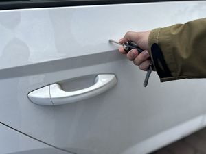 Osoba trzyma klucz w obrębie drzwi samochodowych