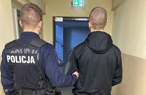 Policjant prowadzi zatrzymanego mężczyznę