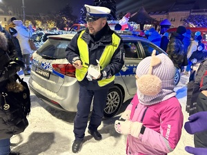 Na zdjęciu widać policjanta rozdającego odblaski na żorskim Rynku.