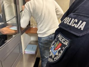 Na zdjęciu widać mężczyznę badanego na zawartość alkoholu w organiźmie oraz policjanta, który uczestniczy w tej czynności.