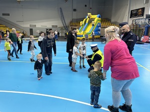 Na zdjęciu widać policjanta, który przykuca i przekazuje odblaskowi chłopcom.