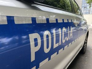 Zdjęcie przedstawia drzwi radiowozu, na którym znajduje się napis Policja