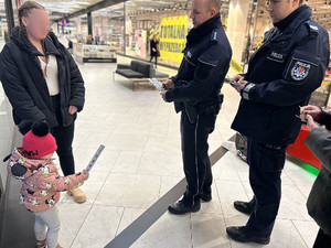 Na zdjęciu widać policjantów przekazujących odblaski kobiecie z dzieckiem.