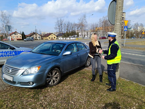 Na zdjęciu widać policjanta oraz kobietę, policjant wręcza kwiat kontrolowanej.