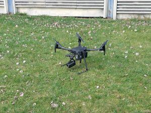Na zdjęciu widać policyjnego drona, który przygotowany jest do startu, stoi na trawniku.