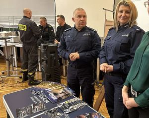 Na zdjęciu widać policjantów przed stanowiskiem promującym służbę w Policji, a w tle strażaków PSP w Żorach.