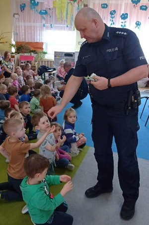 Na zdjęciu widać policjanta, którzy przekazuje dzieciom odblaski.