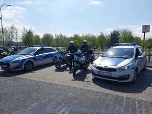 Na zdjęciu widać policyjne motocykle i radiowozy, przy których stoją policjanci.