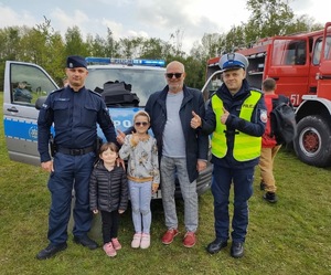 Na zdjęciu widać policjantów oraz mężczyznę z dzieckiem na tle radiowozu.