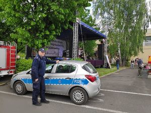 Na zdjęciu widać policjanta przed radiowozem, a w tle znajduje się scena.