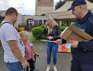 Na zdjęciu widać policjanta, który przekazule odblaski dziewczynce.