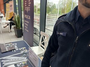 Na zdjęciu widać policjanta, a w tle teren dworca oraz stanowisko promocyjne.