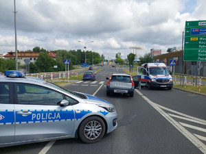 Na zdjęciu widać policyjny radiowóz, pojazd pogotowia ratunkowe i miejsce zdarzenia drogowego.