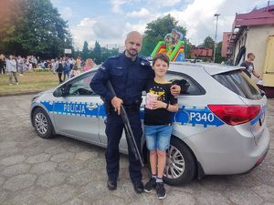 Na zdjęciu widać policjanta przed radiowozem pozującego z chłopcem.