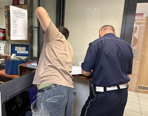 Na zdjęciu widać mężczyznę podczas badania na zawartość alkoholu w organizmie. Obok znajduje się policjant.