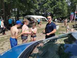 Na zdjęciu widać policjanta rozmawiającego z młodymi uczestnikami akcji.