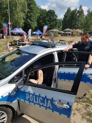 Na zdjęciu widać policjantów, radiowóz i dziecko siedzące w radiowozie.