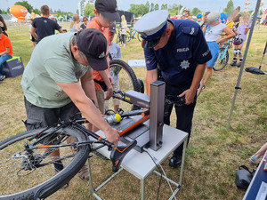 Na zdjęciu widać policjanta oraz osobę znakującą rower.