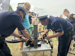 Na zdjęciu widać policjantów pomagających w znakowaniu roweru.