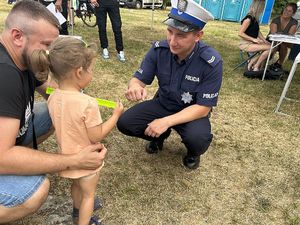Na zdjęciu widać policjanta przybijającego tzw. &amp;quot;żółwika&amp;quot; z dziewczynką. Obok dziewczynki znajduje się mężczyzna.