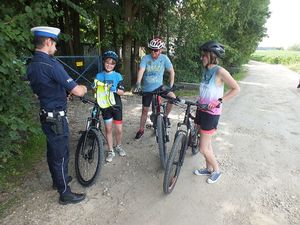 Na zdjęciu widać policjanta oraz rodzinę korzystających z rowerów.