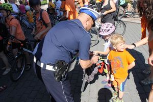Na zdjęciu widać policjanta, który przekazuje dzwonek rowerowy chłopcu.