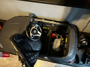 Na zdjęciu widać akumulatorowy szary samochodzik, pod którego siedzeniem znajduje się worek z zawartością białego proszku.